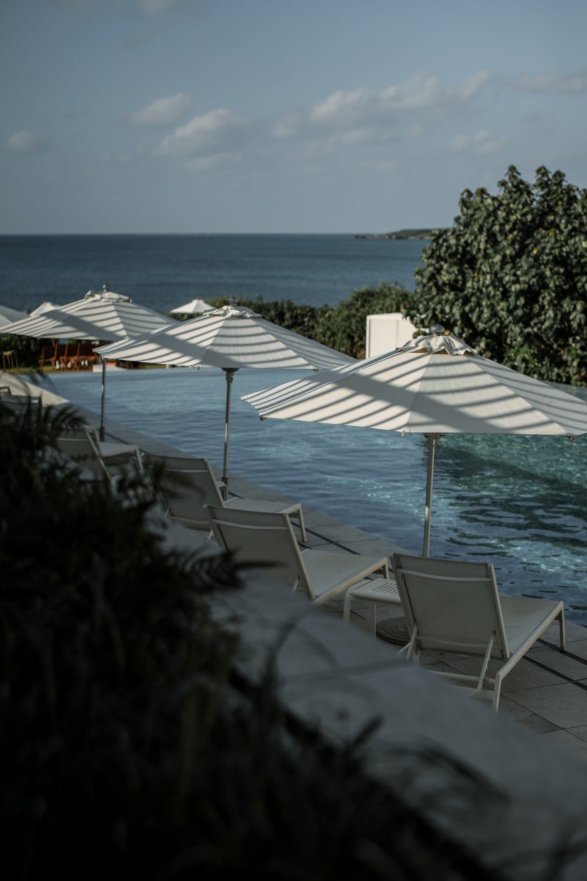 White parasols beside an infinity pool overlooking the sea in Okinawa