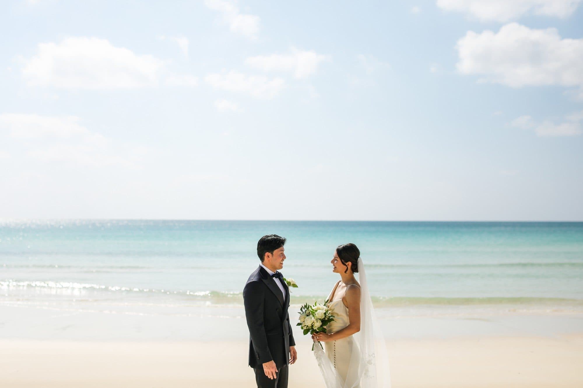 A couple facing each other on a white-sand beach in Okinawa
