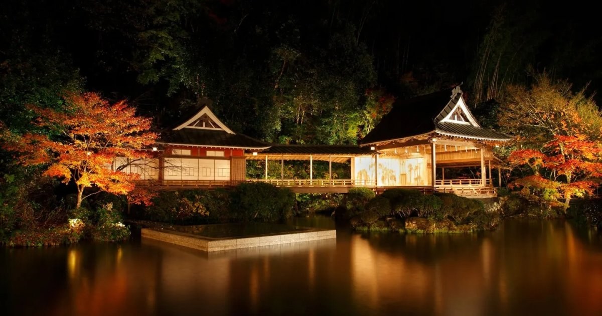 Asaba's Noh stage lit up at night, with autumn maples reflected in the pond